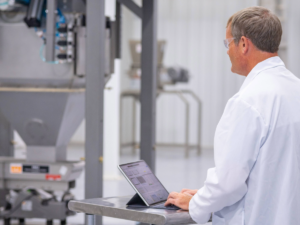 Technician in white lab coat tests a bulk bag unloader.